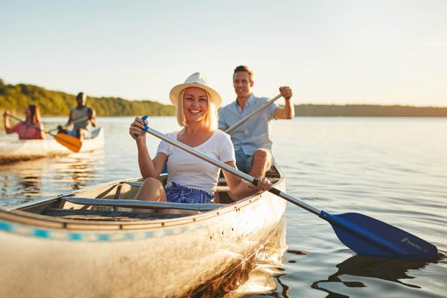 Smiling woman canoeing with friends on a lake in summer